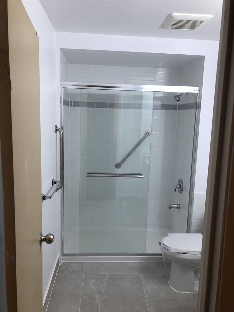 Accessible shower with glass sliding doors and stainless grab bars