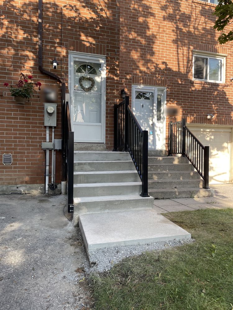 New concrete steps, landing and black metal railings at a brick townhouse unit