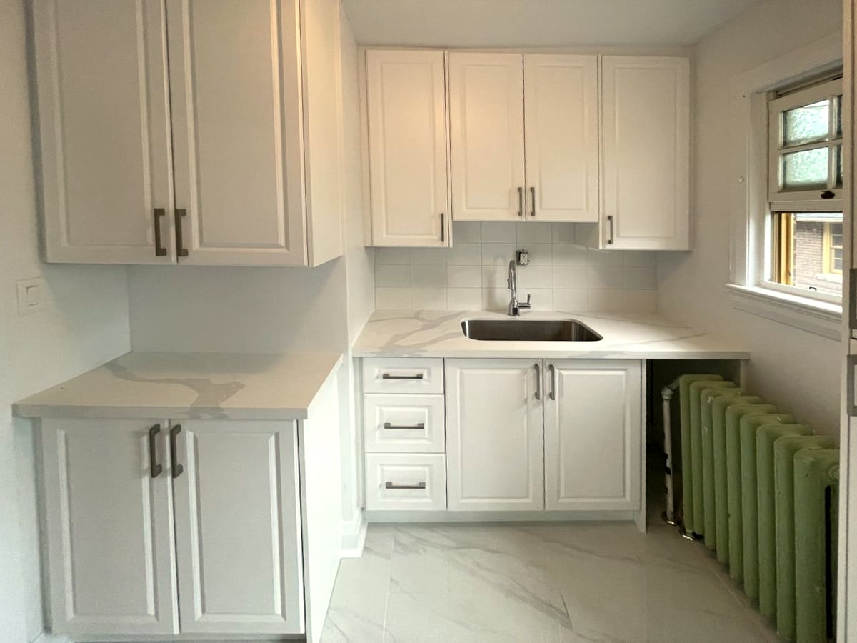 Kitchen renovation by Imagine Work with white cabinets, quartz counters and a tile floor