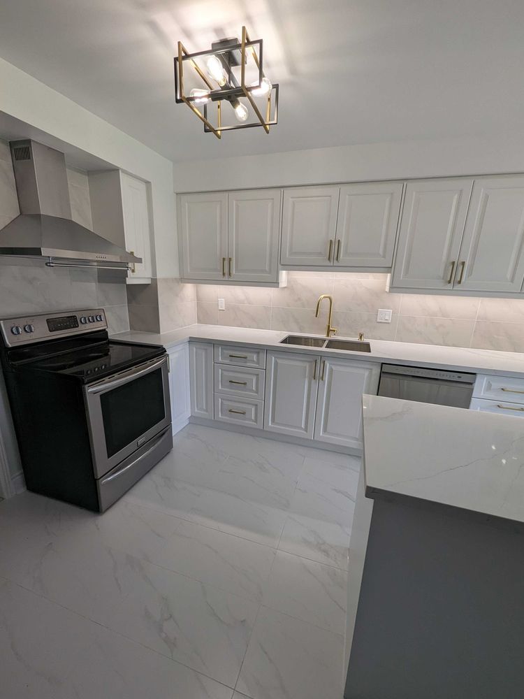 Renovated kitchen with white cabinets, quartz counters, tile backsplash and stainless range hood