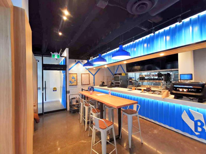High-top table and stools beside the lit blue service counter