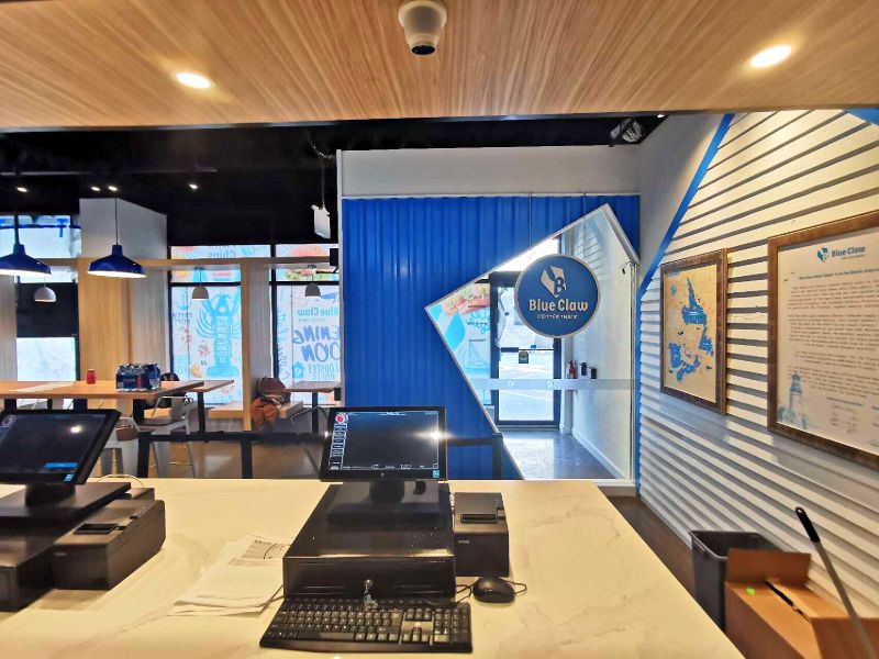 View from the cash counter to the entrance, with a white siding wall and framed map