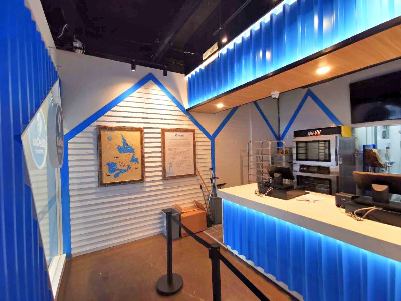 Order area with a house-shaped siding wall and a lit blue counter front