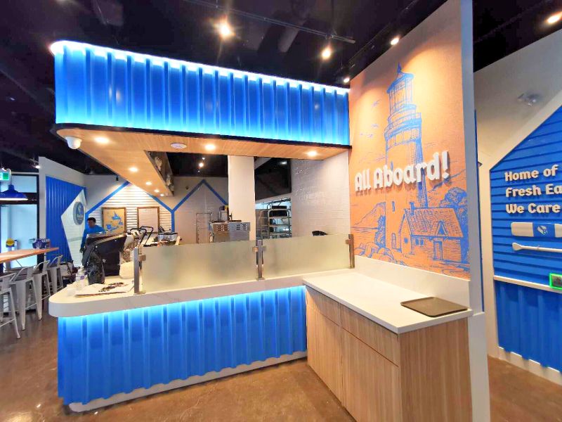 Corner counter with a frosted glass guard and an All Aboard lighthouse mural