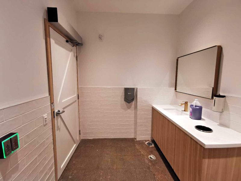 Washroom with a white tile wainscot, wood vanity and brass faucet