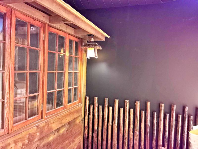 Cabin-style front with wood windows, a lantern and a log post fence