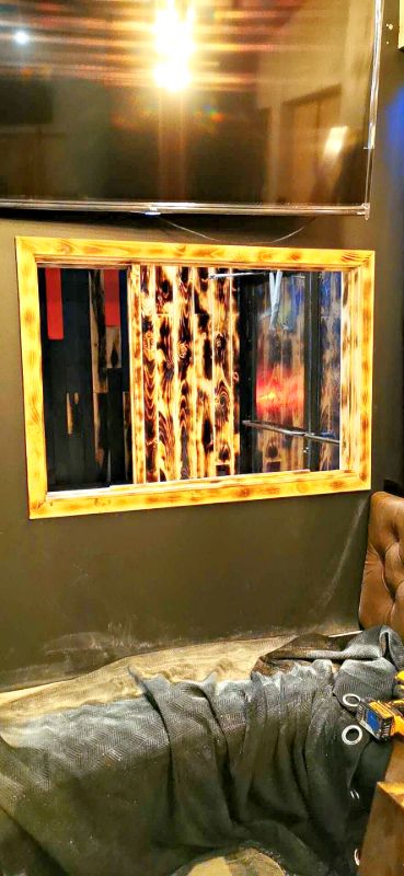 Charred wood frame around a wall mirror above a booth