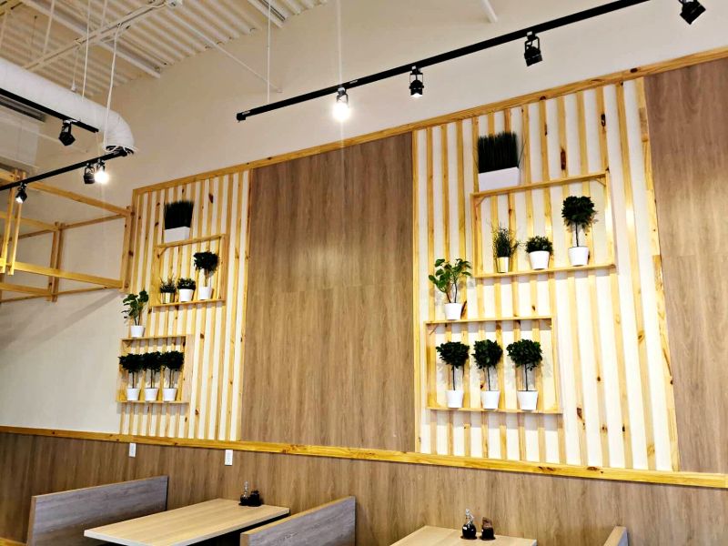 Pine slat feature wall with built-in plant shelves over booth seating