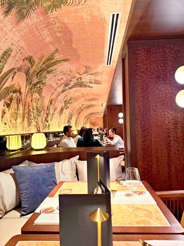 Dining room with a painted palm mural on a vaulted ceiling and hammered wood walls