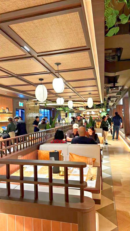 Busy dining room with booths, wood screens and paper lantern pendants