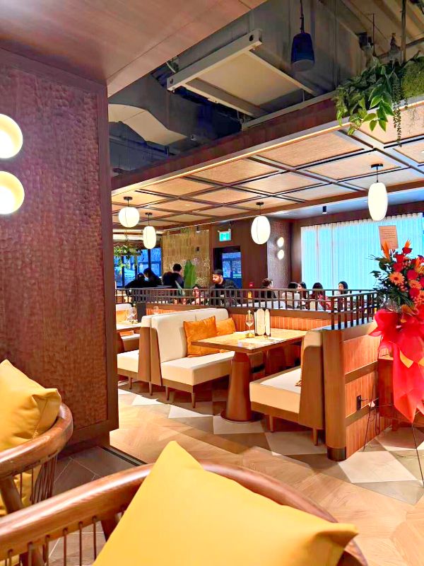 Booths with cream upholstery under a woven coffered ceiling and paper pendants