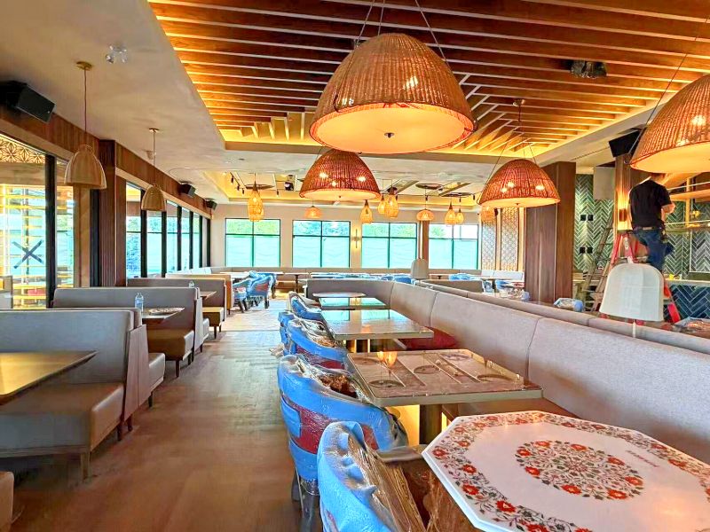 Rows of booths and an inlaid stone table under woven pendants