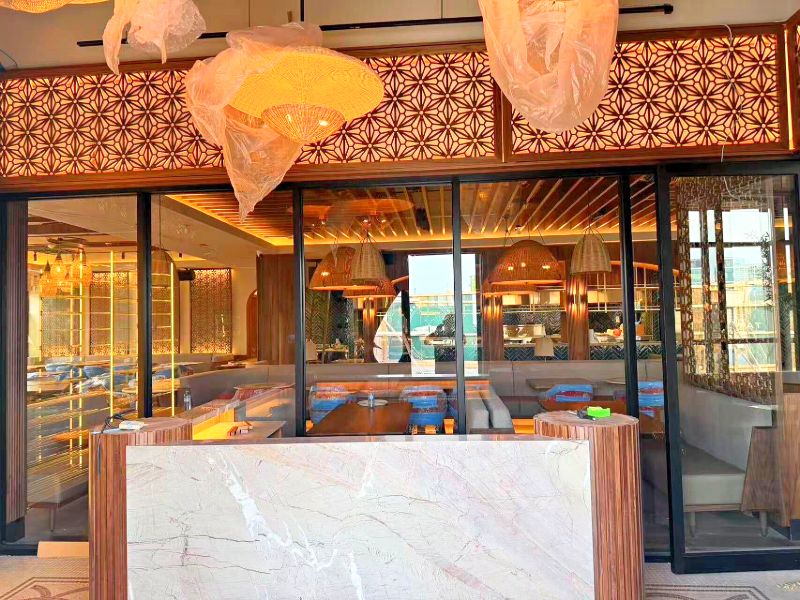 Host stand in white marble and fluted wood, with lit laser-cut screens above a glass wall