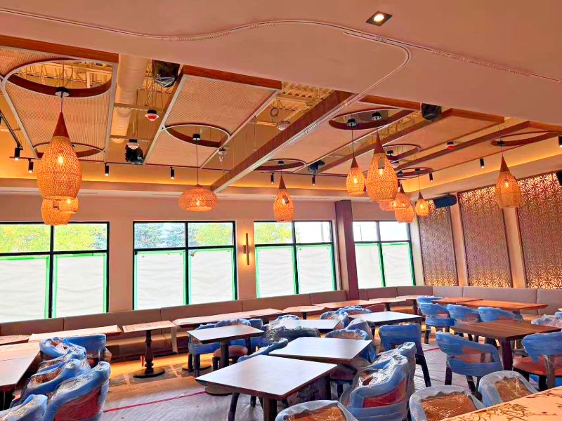 Dining room with woven pendants hung from round ceiling details, chairs still wrapped