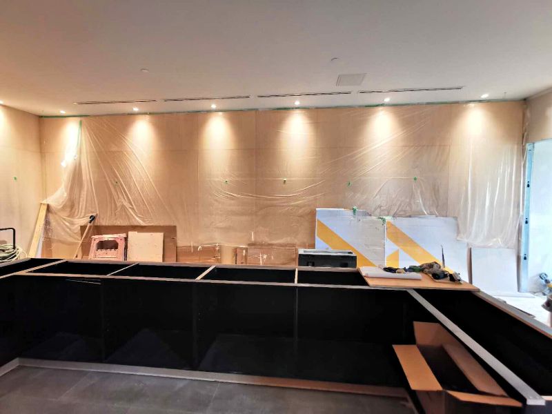 L-shaped counter cabinets installed, wall panels still protected in plastic